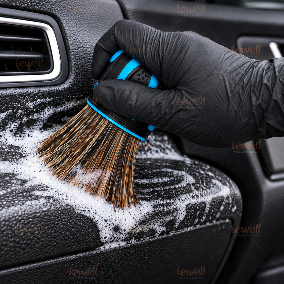 Dome detailing brush scrubbing foamy car interior surface near a vent grille with blue handle