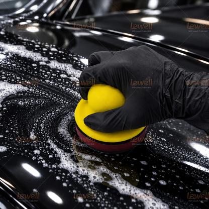 Gloved hand using a yellow foam handheld sanding block on a textured surface