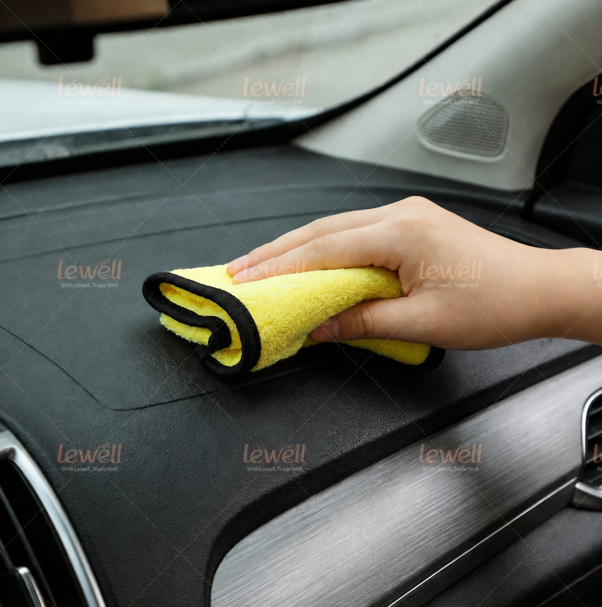 Hand holding folded grey and yellow coral fleece detailing towel on a car surface